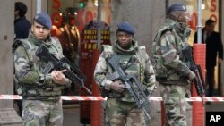 Soldiers stand guard after an attacker with a knife hidden in his bag attacked three soldiers on an anti-terror patrol in front of a Jewish community center in Nice, southern France, Feb. 3, 2015.